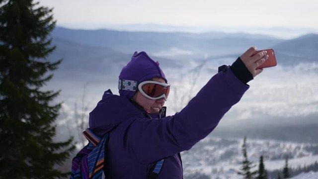a beautiful young girl doing selfie on the ski slopes, 4k