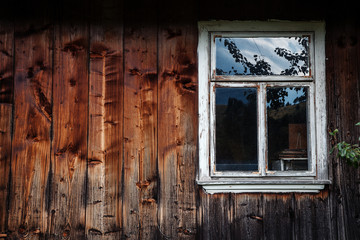 The window of the old wooden log house on the background of wood