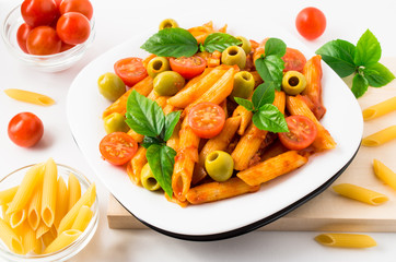 Penne pasta decorated with cherry tomatoes, olives and herbs