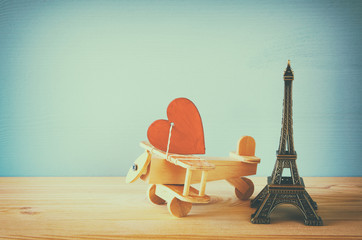 Obraz premium Wooden plane with heart next to Eiffel Tower