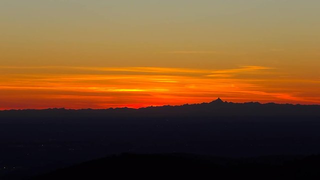 Fiery sunset from mountain pick with thin glazes in the sky evening. Fall season. Orobie alps. Rena pick. Bergamo Italy. In the distance the Monviso.