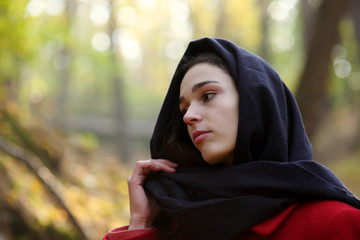 Girl in black scarf walks in autumn park.