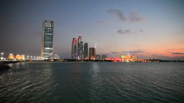 Abu Dhabi skyline at sunset with skyscrapers lit up for the 43rd National day