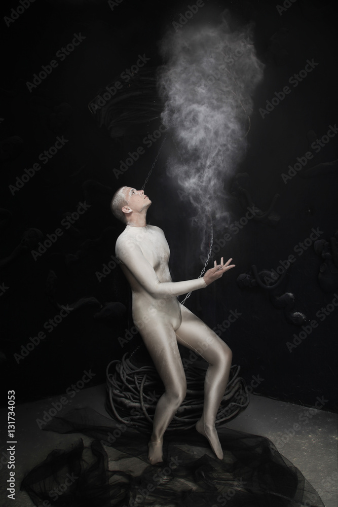 Wall mural dancer in beige spandex jumpsuit posing with flying flour on black background in Studio