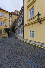 Stone laid lane of Prague going through two rows of classic buildings on either side