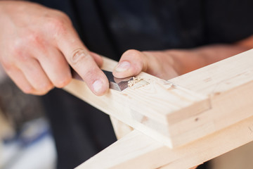 Close up of a furniture maker chiselling a chair joint