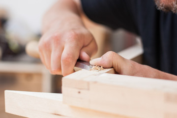 Close up of a furniture maker chiselling a chair joint