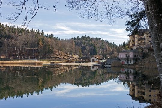 Reflected in blue waters of Lavarone Lake, on the Alpe Cimbra
