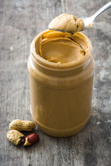 Creamy peanut butter and spoon on wooden background

