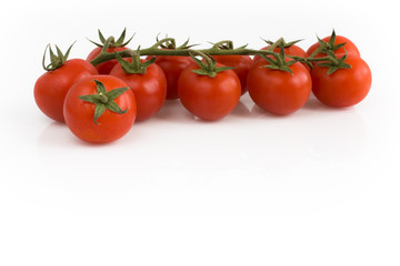 Bunch of cherry tomatoes with green leaves isolated on white background. Still-life studio shot taken with soft-box.