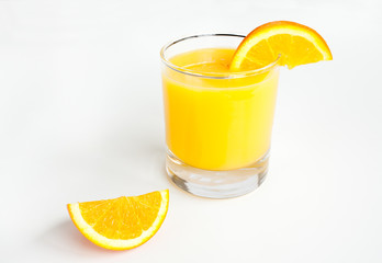 Glass of orange juice and slices on white.