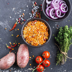 Ingredients for homemade soup with lentils, bulgur, tomatoes, peppers, herbs on a gray marble background. Top view. The concept of seasonal food.