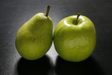 pear and apple on black background