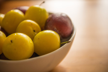 Fresh yellow and purple plums in bowl