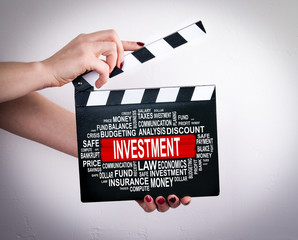Investment concept. Female hands holding movie clapper. 