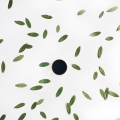 Coffee cup and green leaves pattern. Flat lay, top view