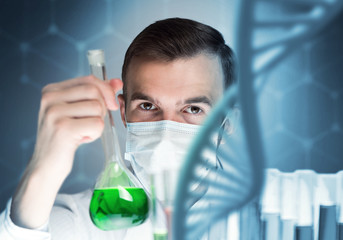 Young scientist mixing reagents in glass flask in clinical laboratory