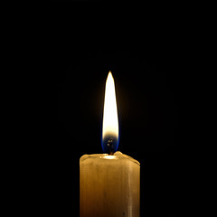 Burning wax candle on a black background
