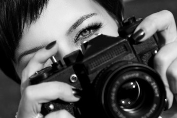 Pretty girl with beautiful eyes make pictures in a city park. Black and white photo.