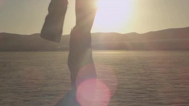 Girl with a fabric runs towards sunset in the desert. Young woman running towards sunrise, slow motion