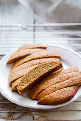 Gingerbread biscotti on a white plate. Wire rack and linen on table