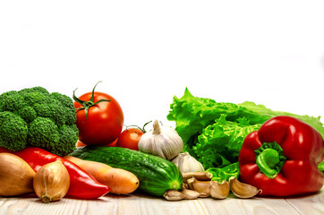 Fresh vegetables for preparation of salad lie on a wooden surface.