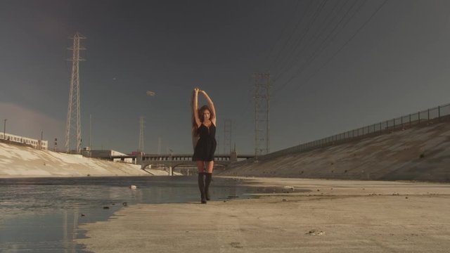 Beautiful girl with the waving fabric positing, dancing, running, walking in the LA River. Industrial area fashion videoshoot.