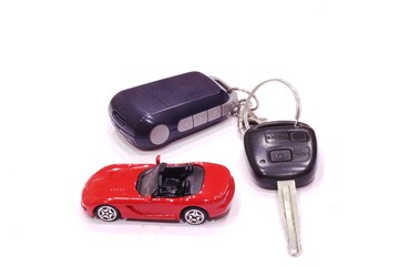 Red toy car and black car keys on white background