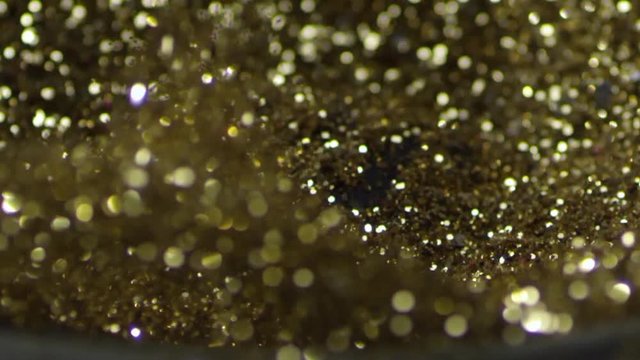 Golden glitter dancing, shivering on black loud speaker. Golden glitter exploding , Slow motion