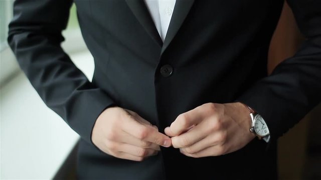 Stylish man dressed in suit buttoning jacket close up. Male hands of confident gentleman adjust outfit preparing for formal evening. Image establishment leadership lifestyle masculinity style success
