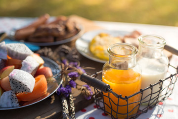 Various breakfast table with fruits egg and sausage, orange juice and milk
