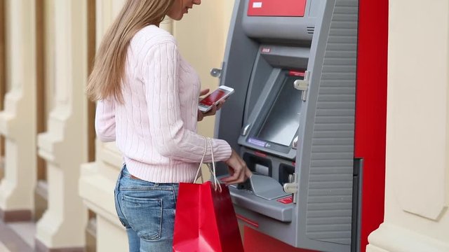 Frustrated young woman stands on against ATM in a shopping center