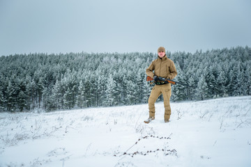Hunter man dressed in camouflage clothing standing in the winter