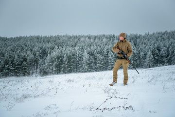 Fototapeta na wymiar Hunter man dressed in camouflage clothing standing in the winter