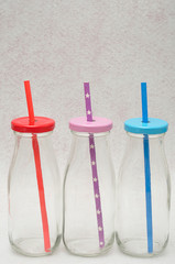 Three glass bottles with straws in the lids
