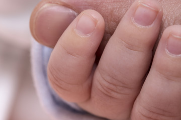 Tiny cute baby hand holding big finger close up