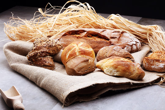 Different kinds of bread rolls on black board from above. Kitchen or bakery poster design.