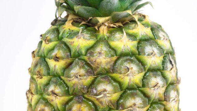 Pineapple rotating on white background. Camera moves down. 4K video.