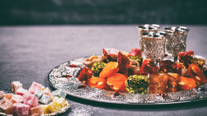 Set of assorted traditional eastern desserts. Arabian sweets on a metal dish. rahat lokum, sherbet, nuts, pistachios, dates, raisins, kadayif in a colorful plates. Selective focus