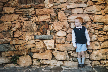 Boy with red hair standing on stone wall