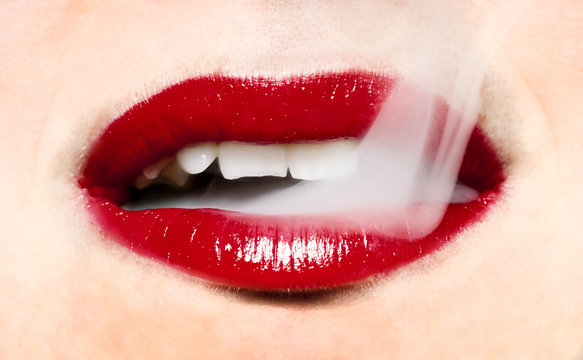 Smoke coming from mouth. Woman with bright red lips.