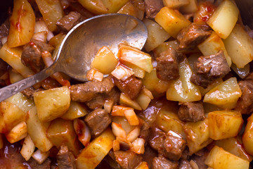 mixing the ingredients. Meat, potatoes, onions, garlic, tomato paste. Cooking bubble and squeak. Process
