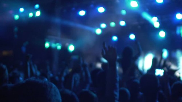 Slow-mo of excited crowd enjoying cool concert, friends hugging and jumping