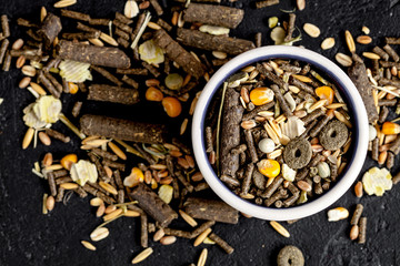 dry food for rodents in bowl dark background top view
