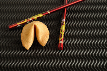 A fortune cookie and a pair of red chopsticks 