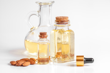 cosmetic almond oil in glass bottle on white background