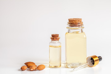 cosmetic almond oil in glass bottle on white background