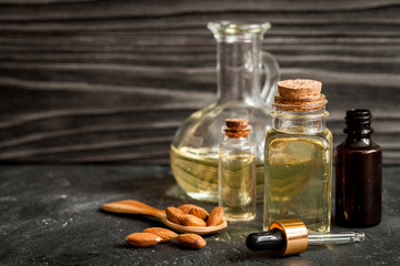 cosmetic almond oil in glass bottle on dark wooden background