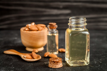 cosmetic almond oil in glass bottle on dark wooden background
