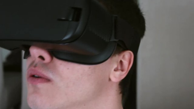 Young man wearing VR Headset and experiencing virtual reality at home. Captured with Blackmagic Production Camera 4K with RAW settings.